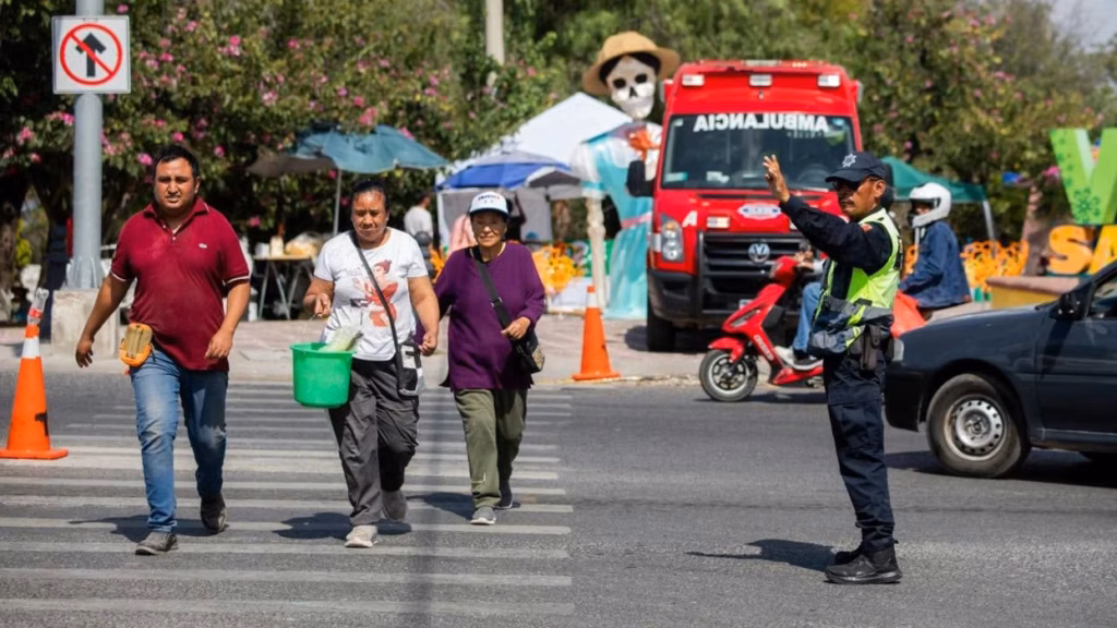 agente-indica-el-paso-a-tres-peatones-en-el-operativo-de-dia-de-muertos-en-san-juan-del-rio-frente-a-una-ambulancia