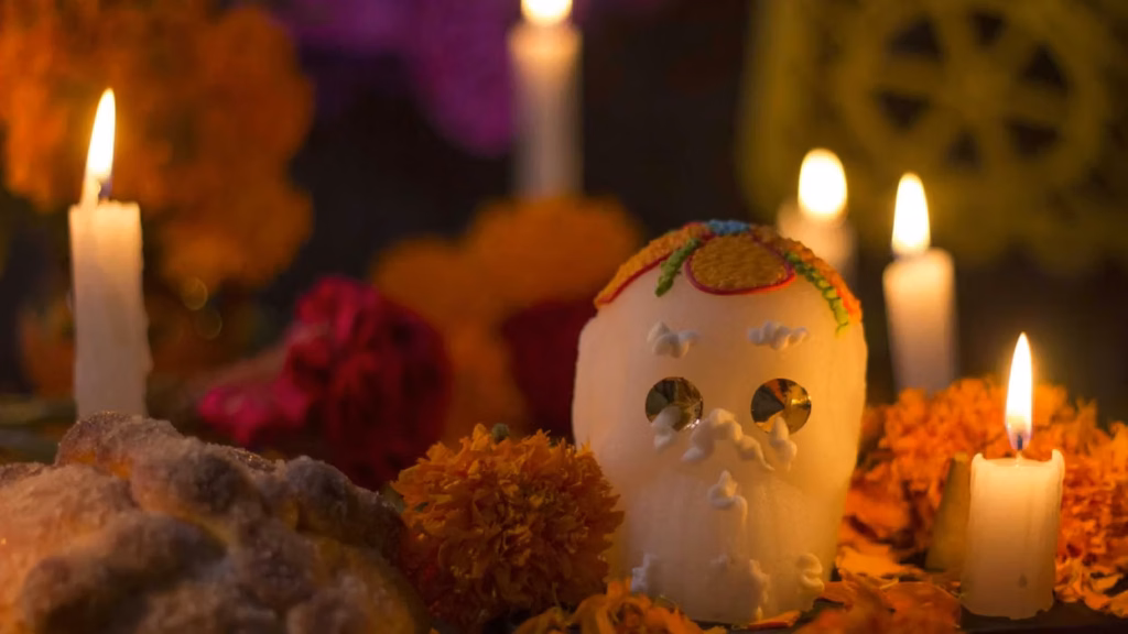 calavera-de-azucar-rodeada-de-veladoras-encendidas-flores-de-cempasuchil-y-pan-de-muerto-en-una-ofrenda-de-dia-de-muertos