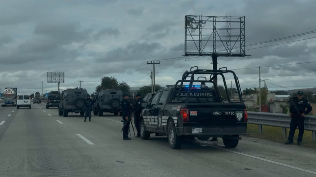 policias-estatales-con-armas-largas-vigilan-dos-vehiculos-blindados-grises-detenidos-junto-a-patrullas-sobre-la-autopista-mexico