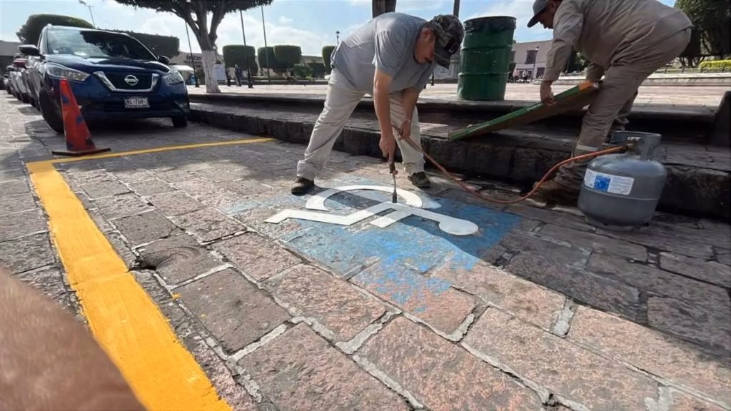 trabajadores-aplican-con-soplete-el-simbolo-de-accesibilidad-en-un-cajon-para-personas-con-discapacidad-del-centro-historico-de