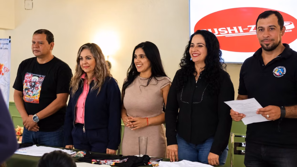 tres-mujeres-participan-en-una-reunion-publica-sentadas-detras-de-una-mesa-con-playeras-en-un-salon-de-san-juan-del-rio